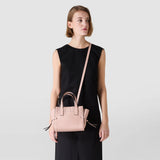 Frontal view: SMALL MARO BAG IN CACHEMIRE LEATHER AND MOSAICO hangs diagonally across a model's body, showing Antique Rose Mosaico, supple Cachemire leather, double handles and knotted side details.