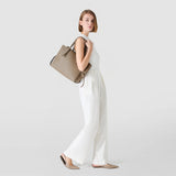 Side view: woman wears MEDIUM MARO BAG IN CACHEMIRE LEATHER AND MOSAICO casually over her shoulder; Sahara Mosaico at top, soft Cachemire leather, leather strips knotted at the sides.