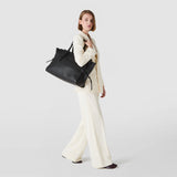Frontal view: MAXI MARO BAG IN CACHEMIRE LEATHER AND MOSAICO is worn over the shoulder of a standing woman; black Mosaico top, large soft body and side leather knots visible.