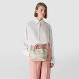 Frontal view: Model wears MINI SECRET BAG IN MOSAICO MESTIERI D'ARTE over the shoulder; small pastel-woven handbag paired with a white blouse and pink trousers against a neutral background.
