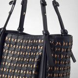 Detail view: BUCKET IN MOSAICO MESTIERI D'ARTE shows woven black leather with gold and rose-colored accents and knotted straps; photographed against a light background.