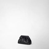 Front view: MINI SECRET CLUTCH BAG IN MOSAICO stands at a slight angle on a light-colored studio surface; the small black leather bag features a woven mosaic pattern and an angular clasp.