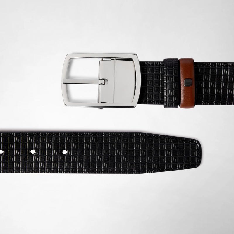 Frontal view: REVERSIBLE BELT IN STEPAN 72 shows a black textured belt with a gunmetal buckle and a brown leather accent loop, lying flat on a light background.