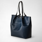 Frontal view of the VERTICAL SECRET TOTE BAG IN STEPAN, made from ocean blue textured Stepan-coated canvas with black leather handles.