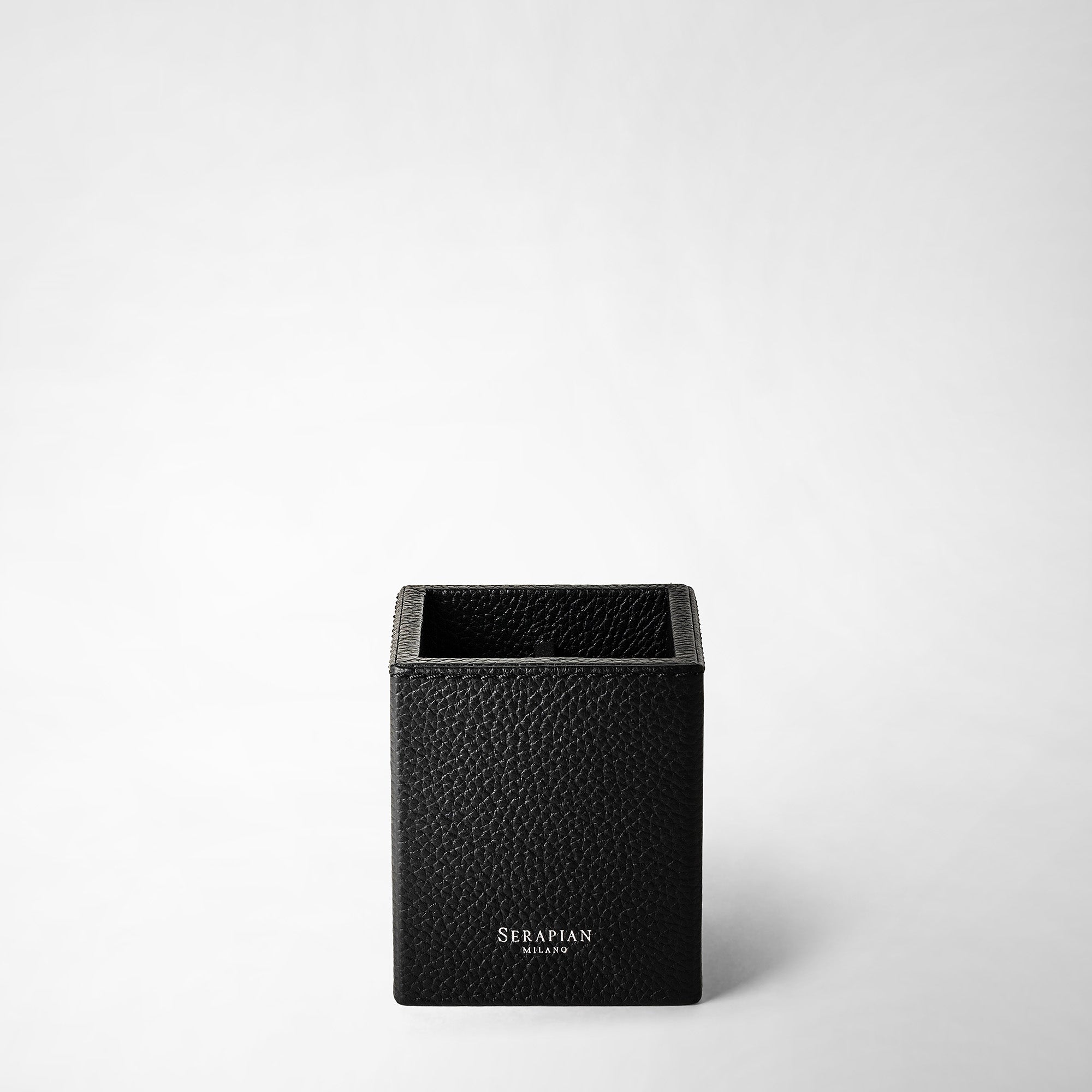 Front view of the PEN POT IN CACHEMIRE LEATHER, an elegant, black, cube-shaped pen holder made from textured Cachemire leather with 'Serapian Milano' inscription on the front.